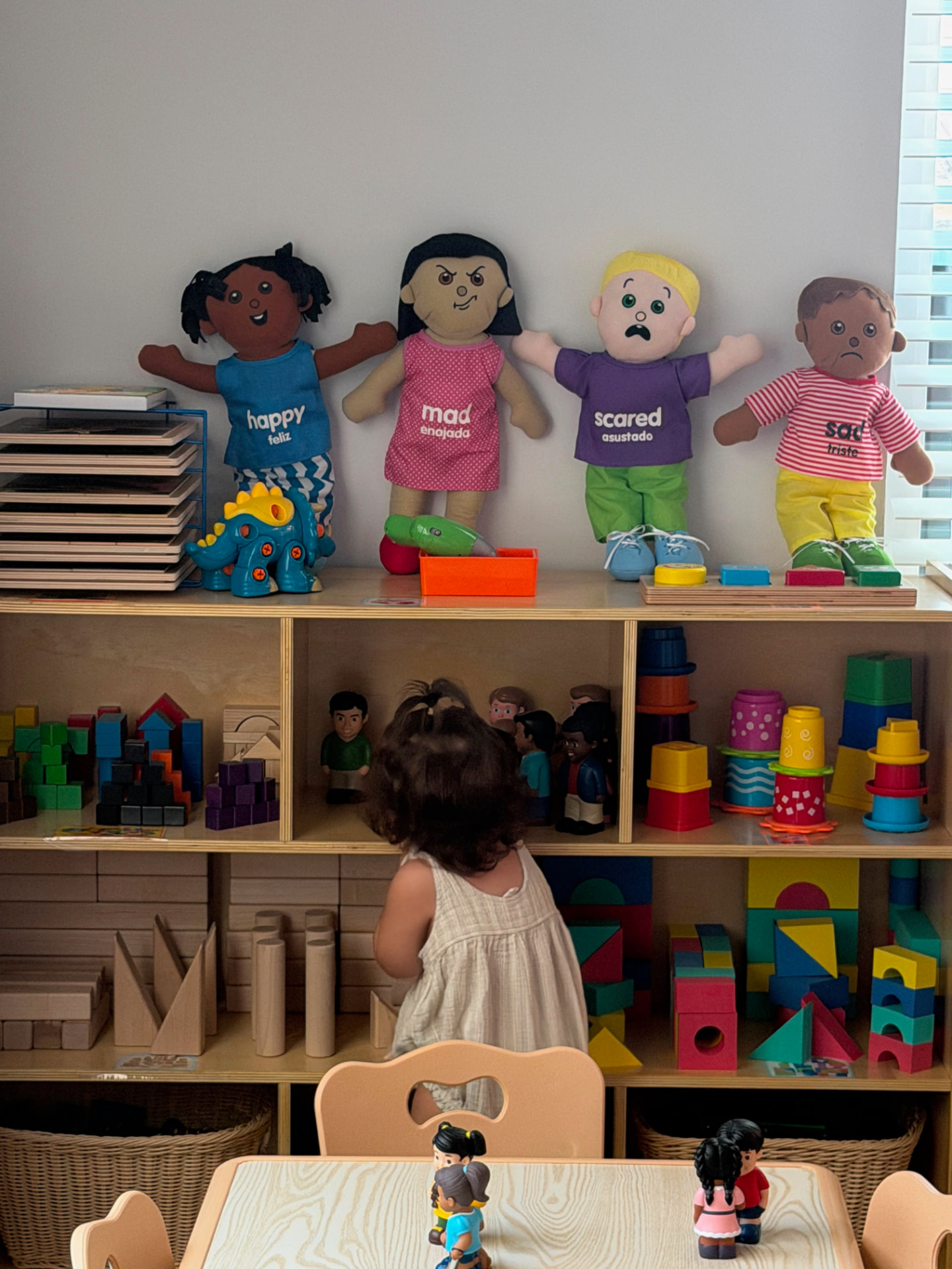 A child exploring blocks, figures, and feelings materials in the classroom